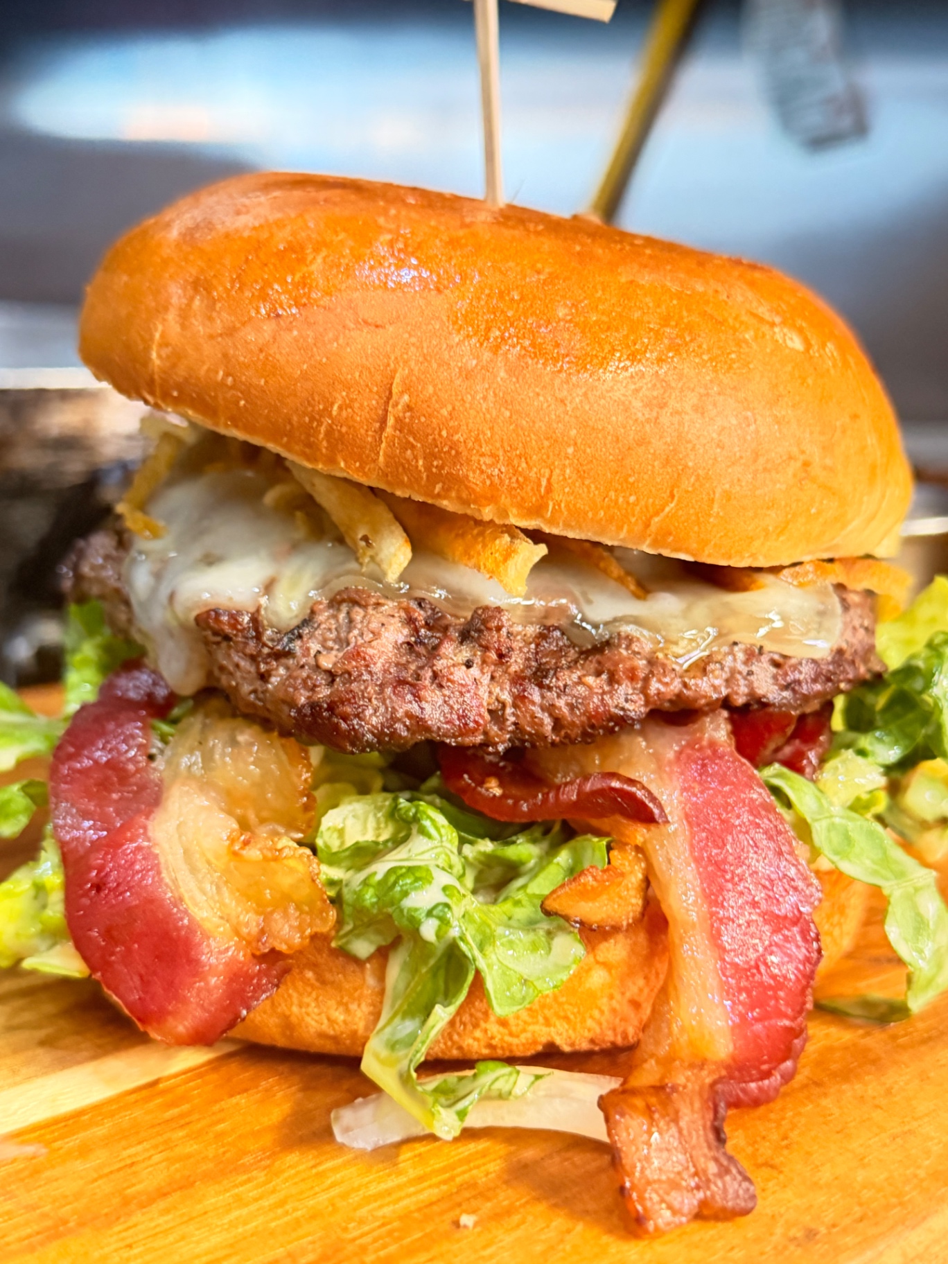 Smash burger stacked with bacon, melted cheese, lettuce and crispy onions