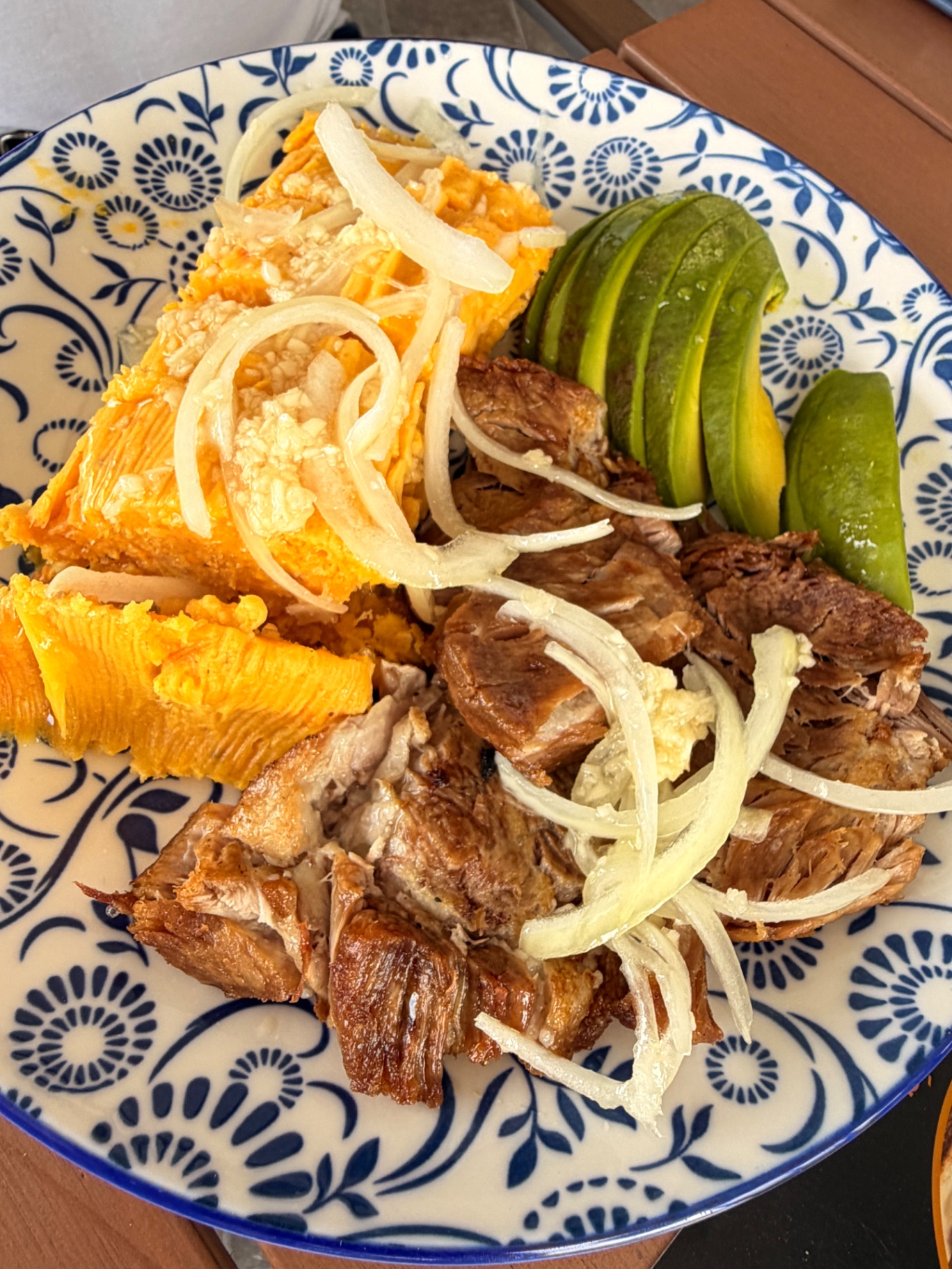 Tamal preparado with roast pork and avocado on hand-painted plate